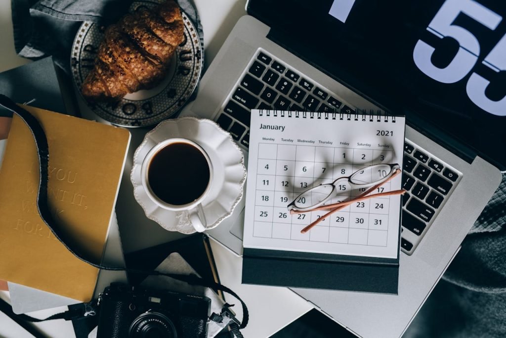 calendar-on-a-laptop-beside-a-cup-of-black-coffee-5386738 A serene workspace setup with coffee, croissant, laptop, and calendar, ideal for organizing plans.